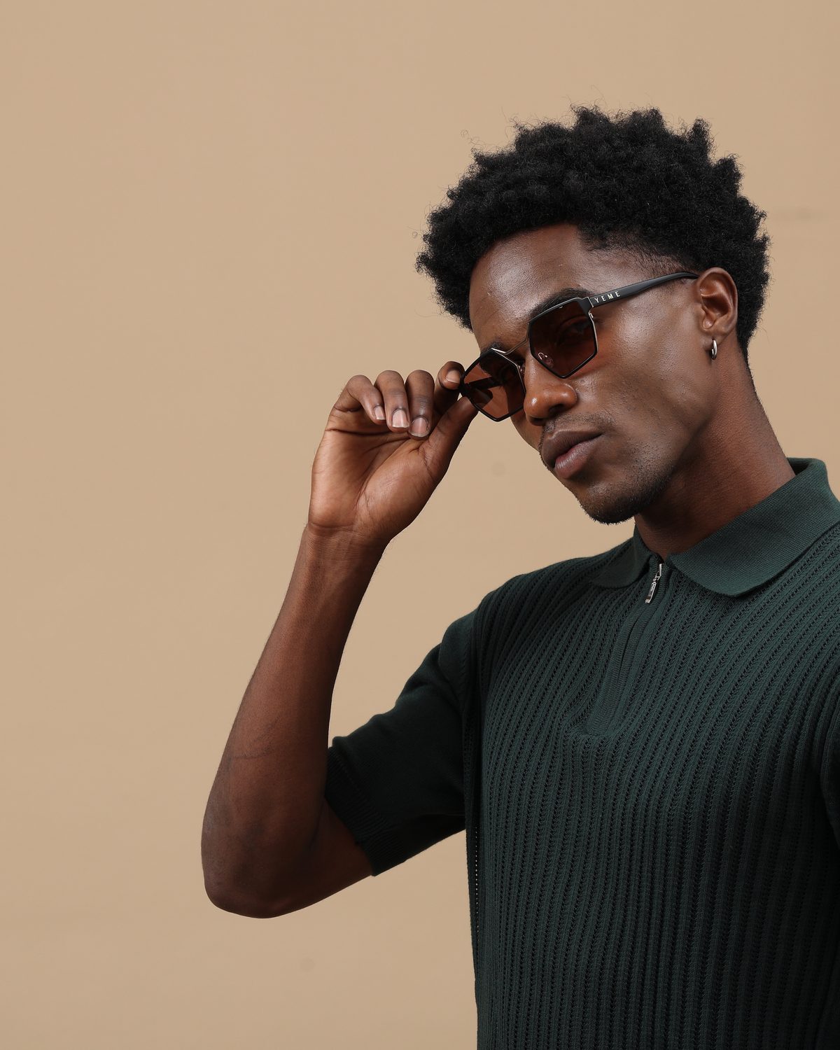 Man in a green knit polo adjusting YEME Venom sunglasses