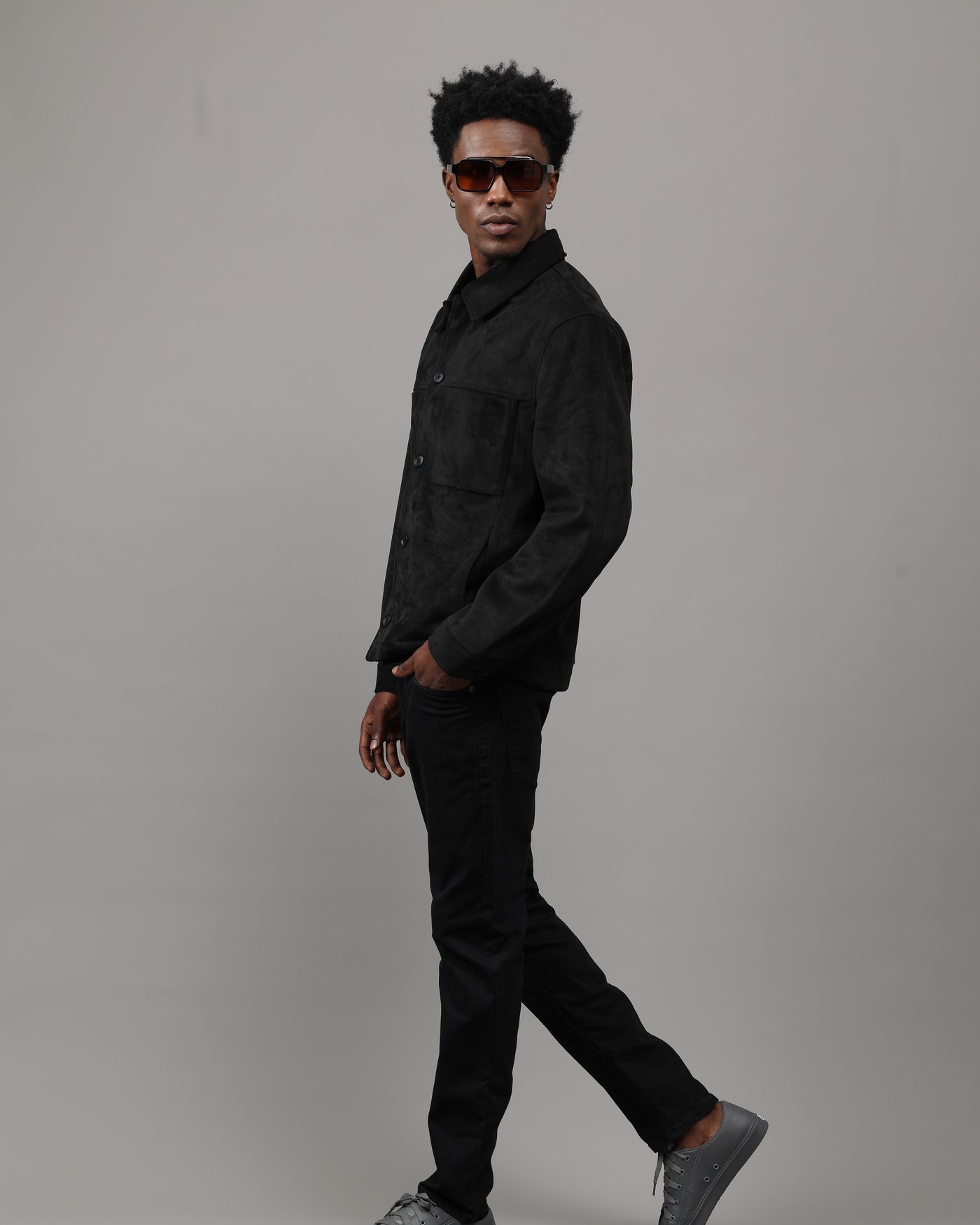 Man in a black suede jacket walking, wearing YEME sunglasses